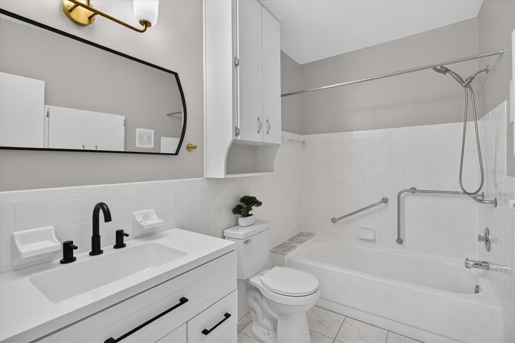 A bathroom features a white vanity, a toilet, and a shower-tub combination with grab bars — 2295 AMERICUS BOULEVARD E UNIT 59, CLEARWATER, FL