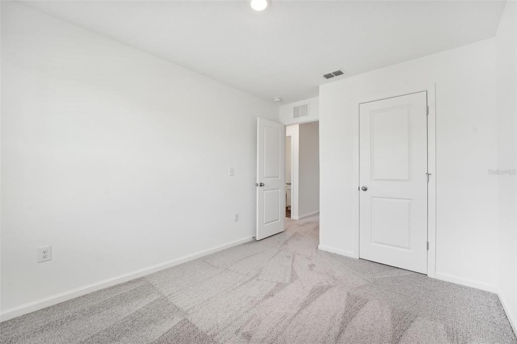 A bedroom with white walls, gray carpet, and two closed white interior doors — 14848 LUCCA WAY, DADE CITY, FL