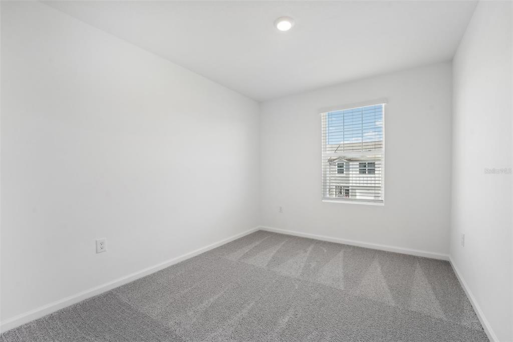 An empty bedroom features white walls, gray carpet, a single window, and a ceiling light — 14848 LUCCA WAY, DADE CITY, FL