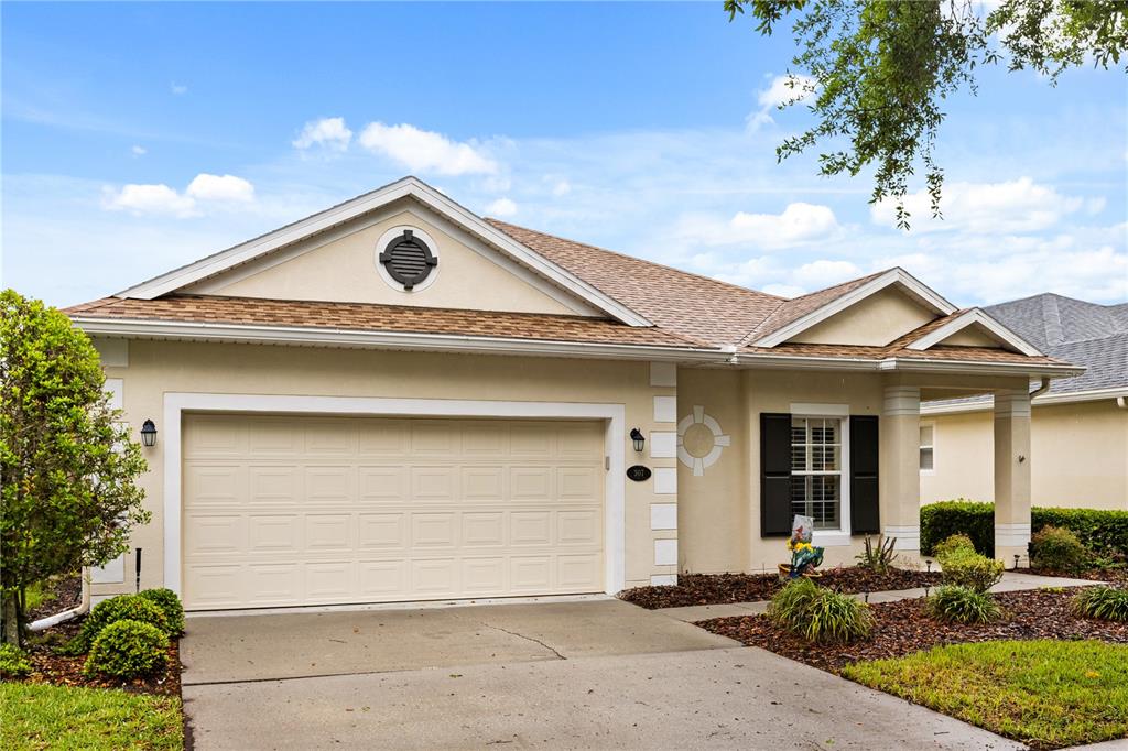 A single-story house with a beige stucco exterior, a two-car garage, and a covered entryway — 307 HERON POINT WAY, DELAND, FL
