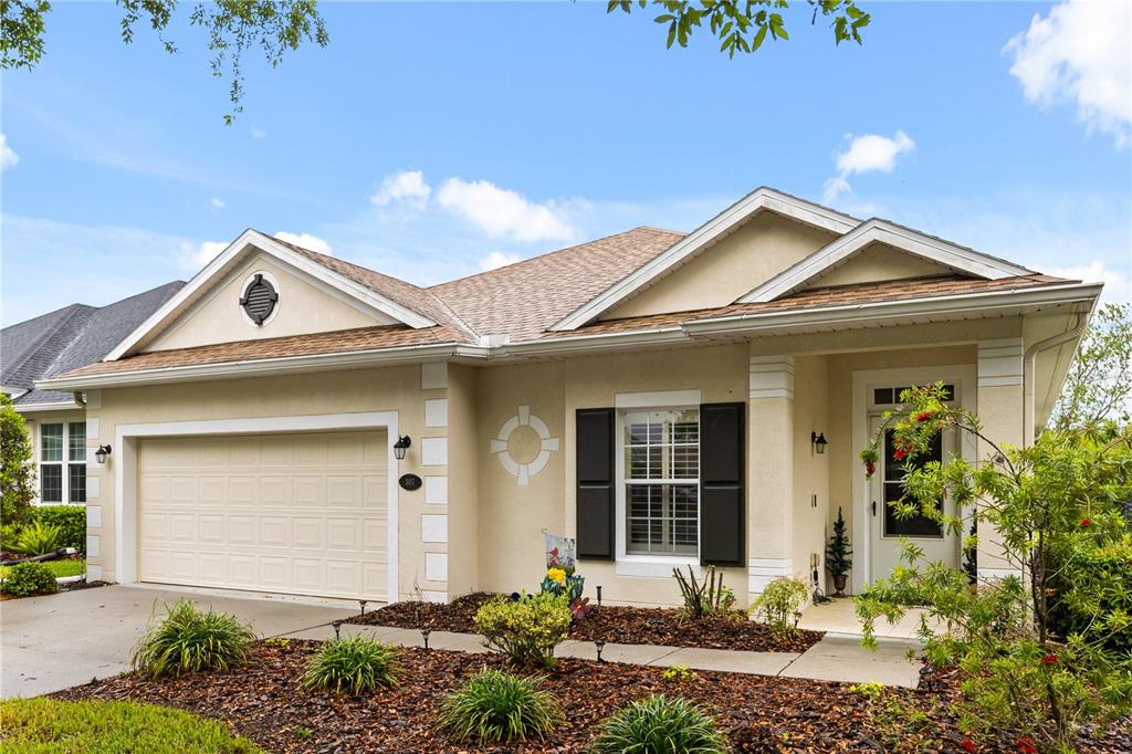 A single-story house with a beige stucco exterior, a two-car garage, and a front porch — 307 HERON POINT WAY, DELAND, FL