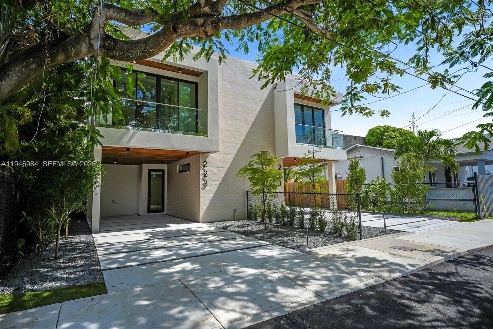 A modern two-story duplex with concrete driveways, glass balconies, and wood-paneled overhangs — 223 NW 51st St, Miami FL 33127, MIAMI, FL