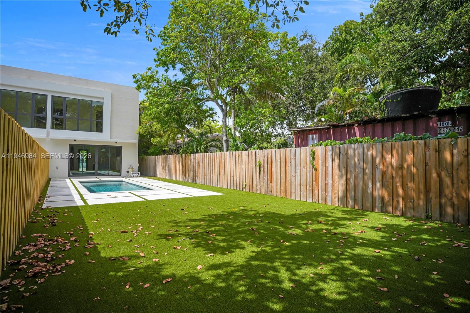 A modern house with a pool and artificial turf lawn enclosed by a wooden fence — 223 NW 51st St, Miami FL 33127, MIAMI, FL
