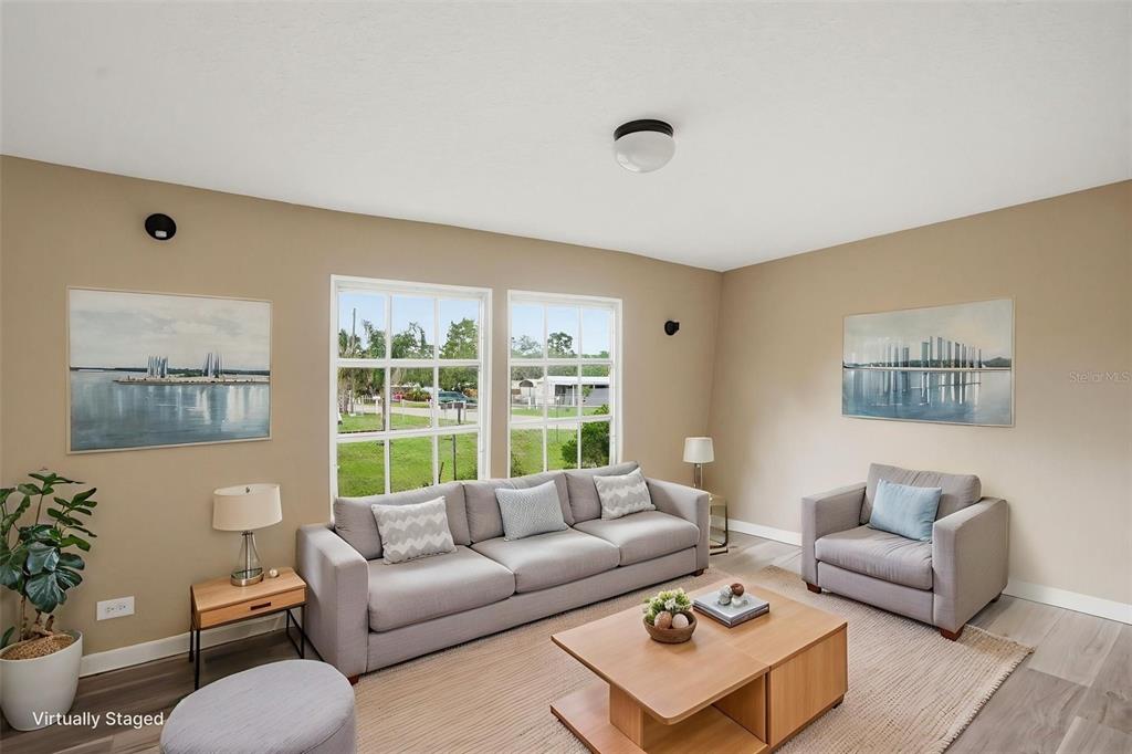 A living room with a gray sofa, armchair, coffee table, and two windows — 11311 ALTOONA AVENUE, NEW PORT RICHEY, FL