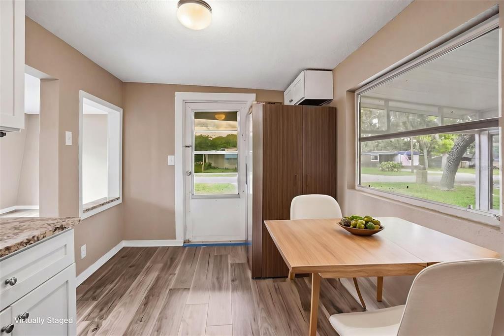 A dining area features wood-look flooring, a table with two chairs, and a glass door — 11311 ALTOONA AVENUE, NEW PORT RICHEY, FL