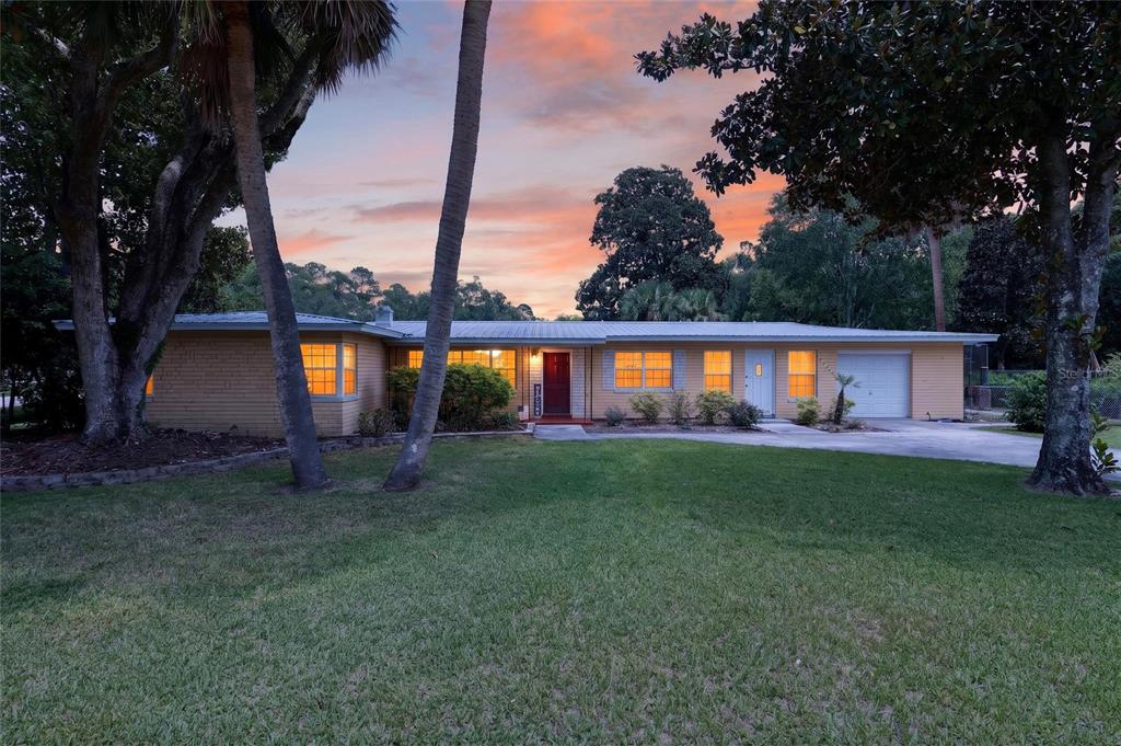 A single-story yellow brick house with a metal roof sits behind a grassy lawn — 223 NW 7TH STREET, WILLISTON, FL
