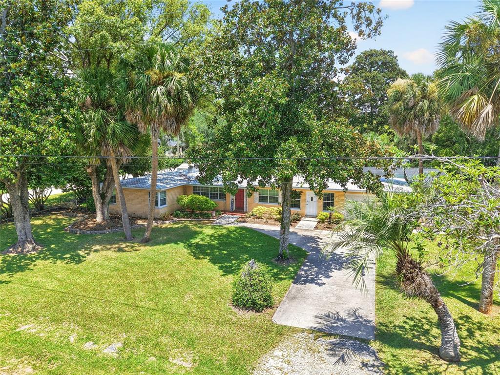 An exterior view of a single-story brick house with a driveway and mature palm trees — 223 NW 7TH STREET, WILLISTON, FL