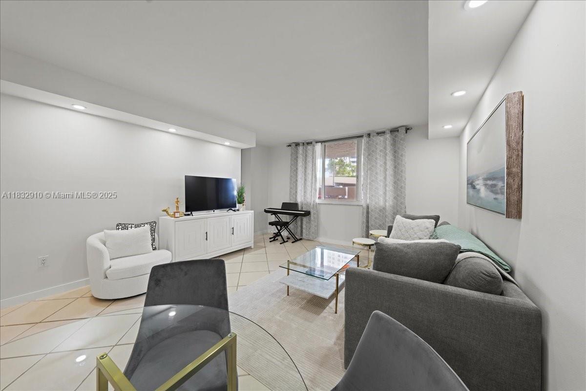 A living room features tile flooring, a gray sofa, a white armchair, and a television console — 540 Brickell Key Dr # 412, Miami FL 33131, MIAMI, FL