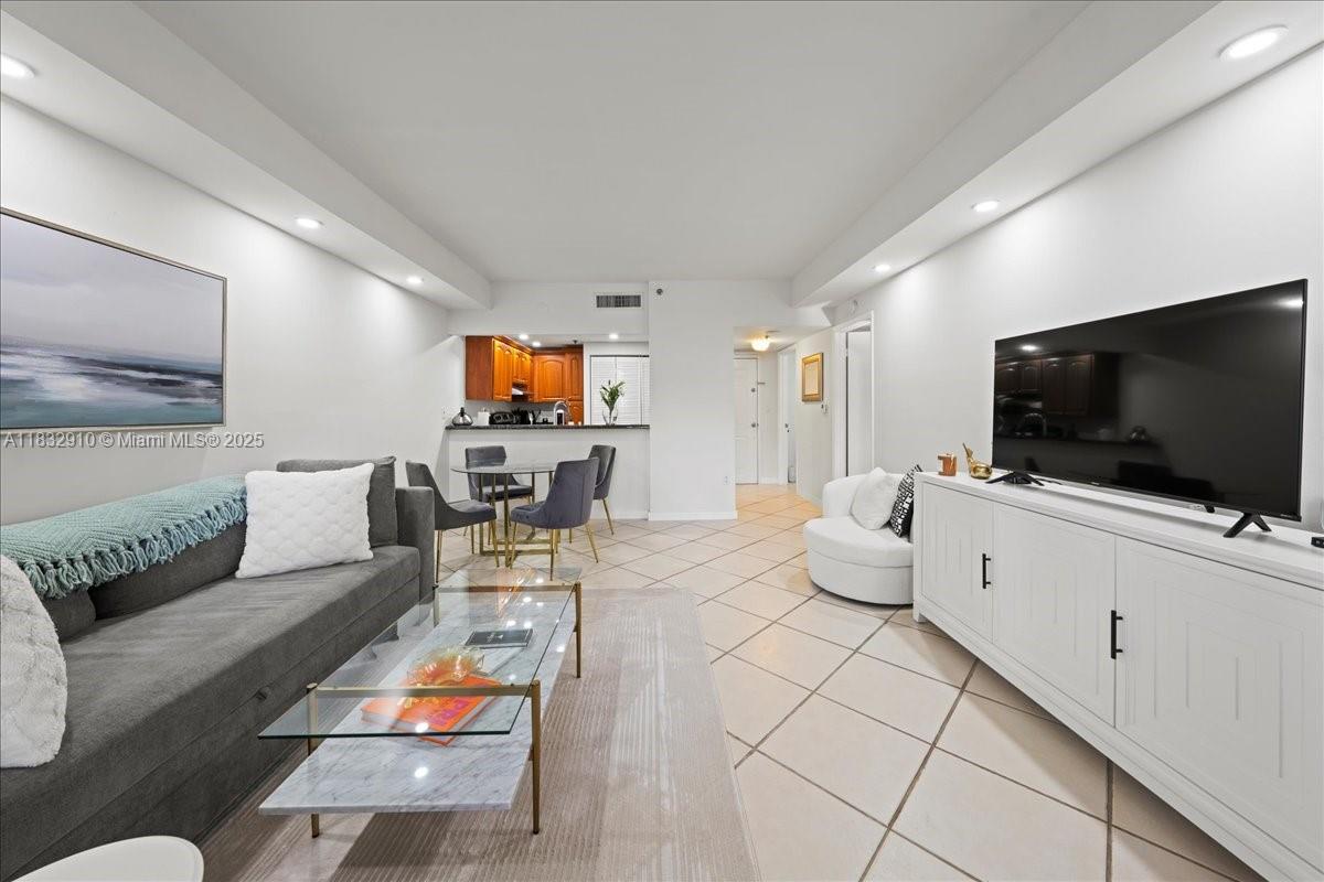 This living room features tile flooring, a grey sofa, a glass coffee table, and a television — 540 Brickell Key Dr # 412, Miami FL 33131, MIAMI, FL