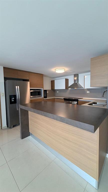 A modern kitchen features light wood cabinetry, a dark countertop island, and stainless steel appliances — 48 Av. Luis Muñoz Rivera CONDO. AQUABLUE, HATO REY UNIT 1705, SAN JUAN, PR