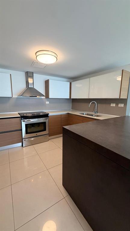 A modern kitchen features light wood cabinets, white upper cabinets, stainless steel appliances, and tile flooring — 48 Av. Luis Muñoz Rivera CONDO. AQUABLUE, HATO REY UNIT 1705, SAN JUAN, PR