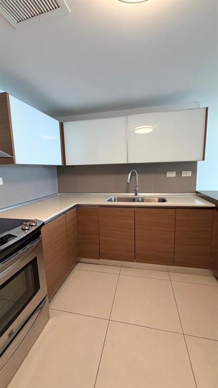 A modern kitchen features wood-grain lower cabinets, white upper cabinets, and stainless steel appliances — 48 Av. Luis Muñoz Rivera CONDO. AQUABLUE, HATO REY UNIT 1705, SAN JUAN, PR