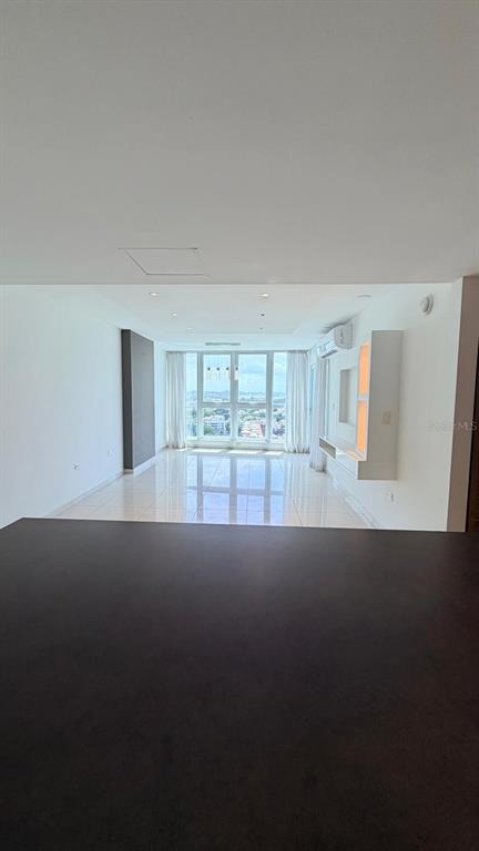 An open-concept living area features white walls, tile flooring, and floor-to-ceiling windows with city views — 48 Av. Luis Muñoz Rivera CONDO. AQUABLUE, HATO REY UNIT 1705, SAN JUAN, PR