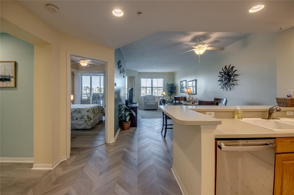 A kitchen counter overlooks a living area with herringbone flooring and a bedroom doorway — 2090 MATECUMBE KEY ROAD UNIT 1202, PUNTA GORDA, FL