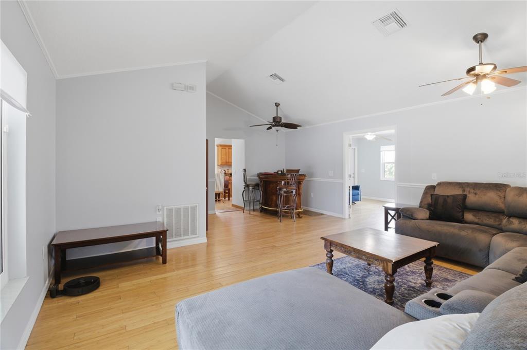 A living room with light wood floors, a vaulted ceiling, a bar, and a sectional sofa — 602 LAKE DRIVE, SEBASTIAN, FL
