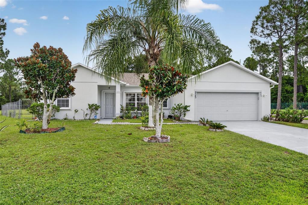 A single-story house with a white exterior, a two-car garage, and a palm tree — 925 GILLINGHAM COURT, KISSIMMEE, FL