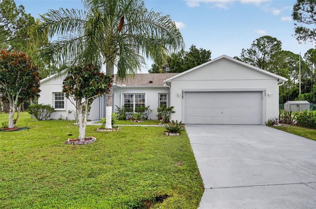 The exterior of a single-story house features a gray front door, a lawn, and landscaping — 925 GILLINGHAM COURT, KISSIMMEE, FL