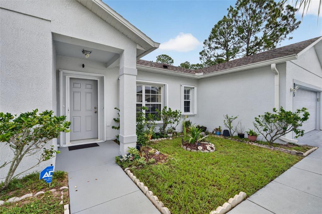 A living room features tile flooring, a gray sofa, an armchair, and a front door — 925 GILLINGHAM COURT, KISSIMMEE, FL