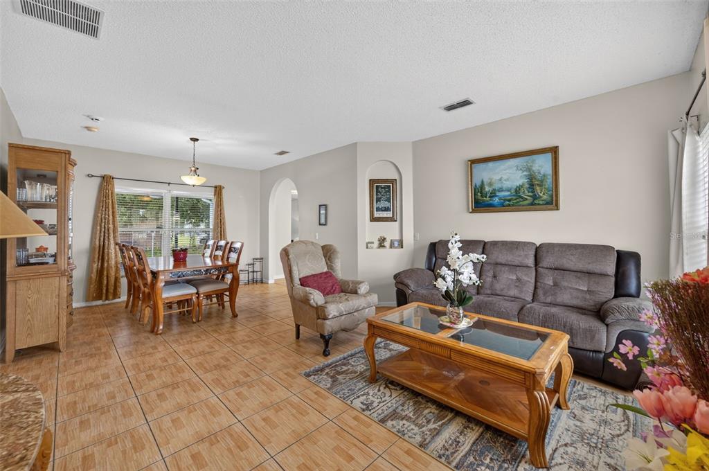 A living room features a gray sofa, a glass-topped wooden coffee table, and tile flooring — 925 GILLINGHAM COURT, KISSIMMEE, FL