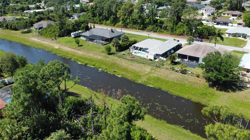 An aerial view shows a canal flowing between residential houses with screened-in pools — Lot 6, GARDENSIDE CIRCLE, NORTH PORT, FL