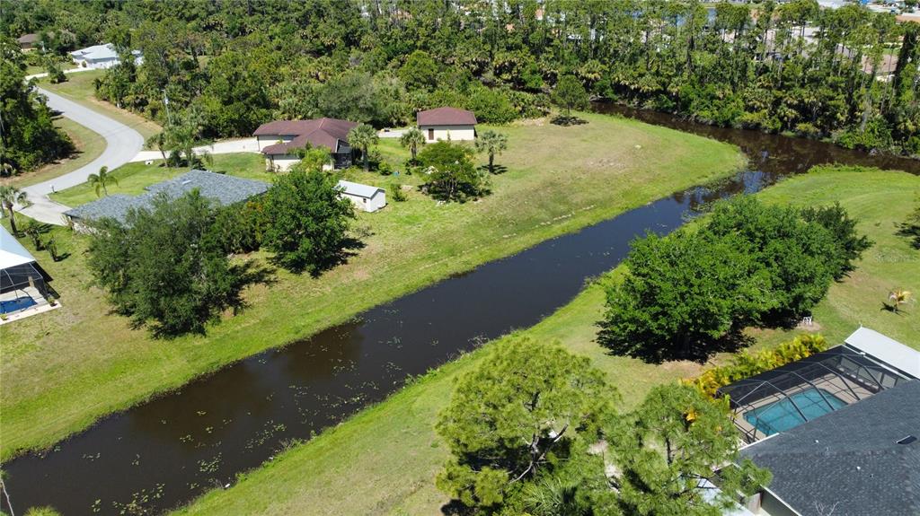 An aerial view shows houses, a canal, and surrounding trees in a residential neighborhood — Lot 6, GARDENSIDE CIRCLE, NORTH PORT, FL