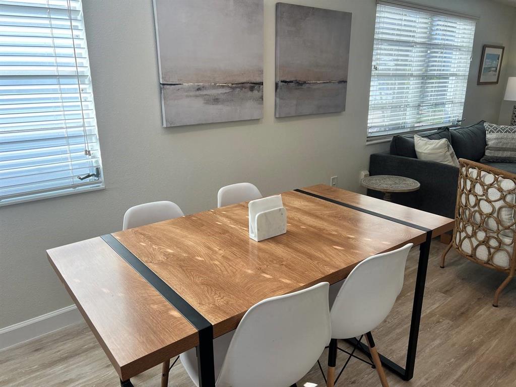 A dining area features a wooden table with black metal accents and four white chairs — 6020 MIDNIGHT PASS ROAD UNIT 45, SARASOTA, FL