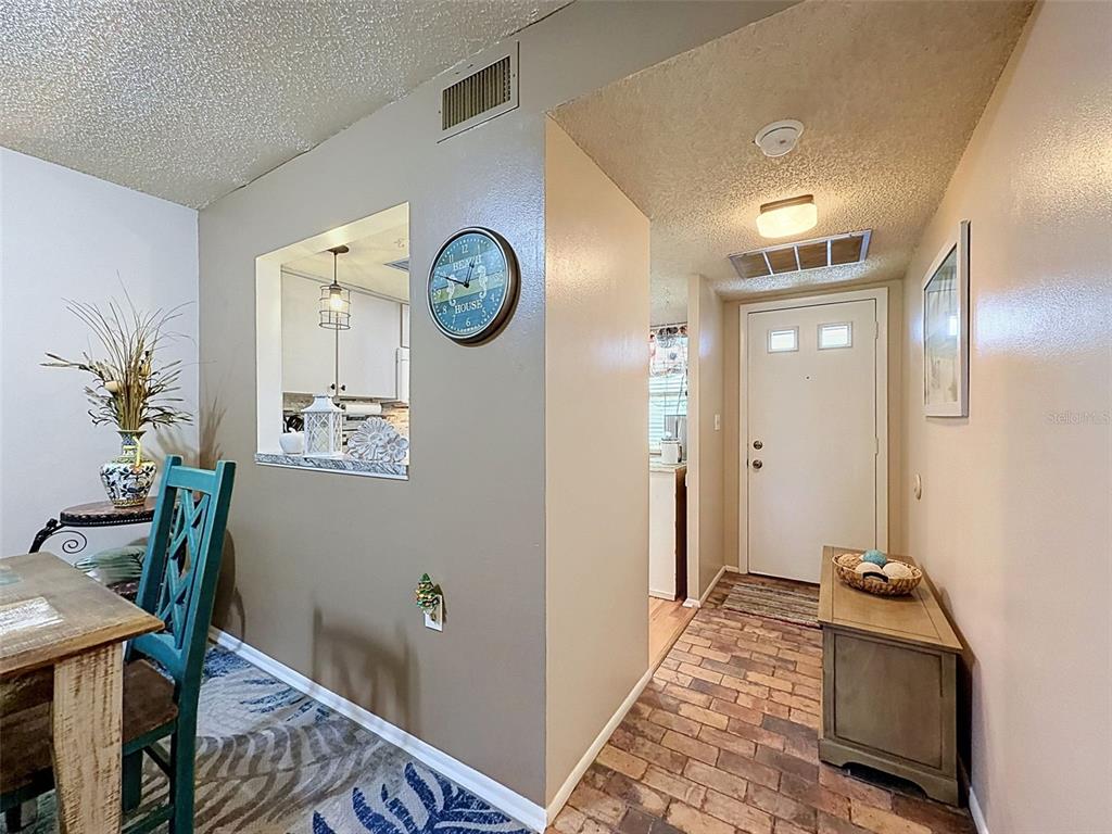 An interior view shows a dining area with a pass-through window, tile flooring, and entryway — 8220 SEVEN OAKS COURT UNIT 5, PORT RICHEY, FL