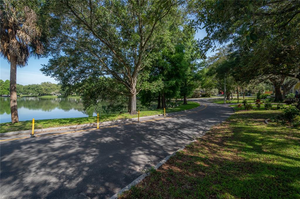 A paved path winds alongside a lake bordered by trees and yellow bollards — 5530 N 9TH STREET UNIT 2, TAMPA, FL