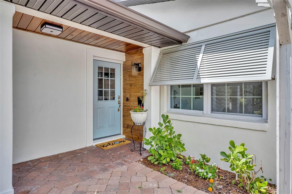 A light blue front door with a window sits under a covered porch with pavers — 1611 CHESTNUT AVENUE, WINTER PARK, FL