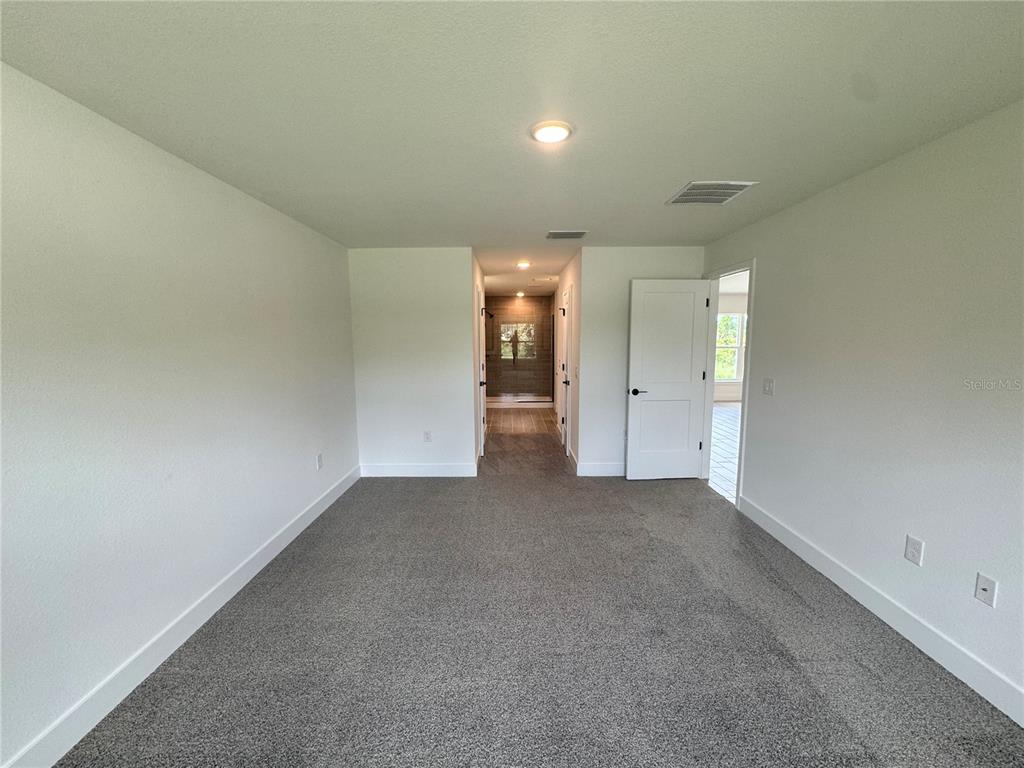 A carpeted bedroom features a doorway leading to a tiled bathroom and an open door — 5923 GIFFEN AVENUE, NORTH PORT, FL