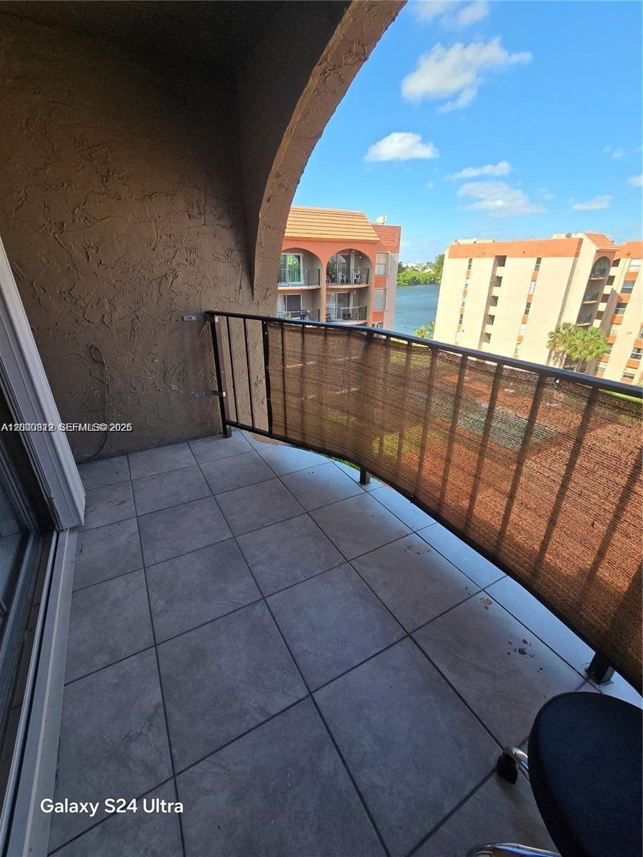 A balcony with tiled flooring, a metal railing, and a privacy screen overlooks a waterway — 5201 NW 7th St # 609W, Miami FL 33126, MIAMI, FL