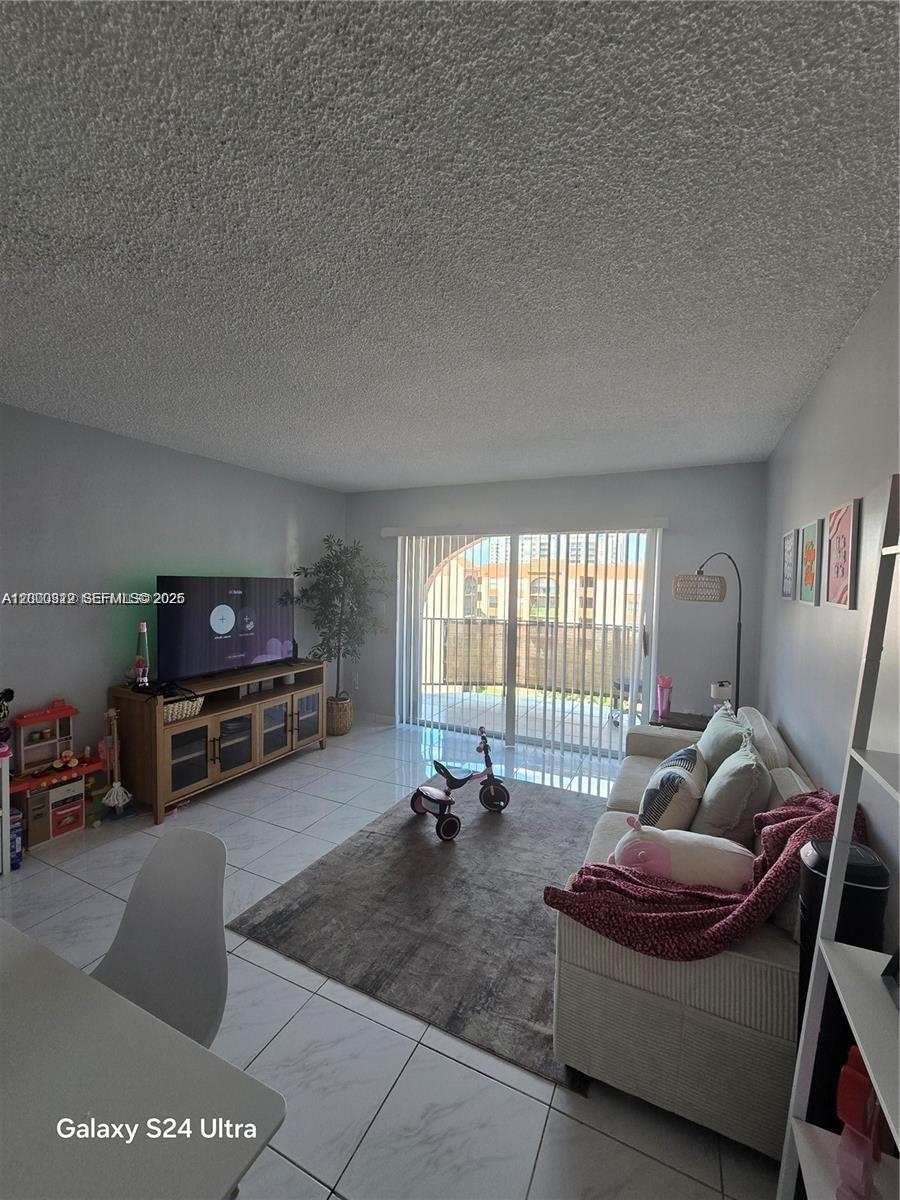 A living room features a television on a wooden stand, a sofa, and a balcony — 5201 NW 7th St # 609W, Miami FL 33126, MIAMI, FL