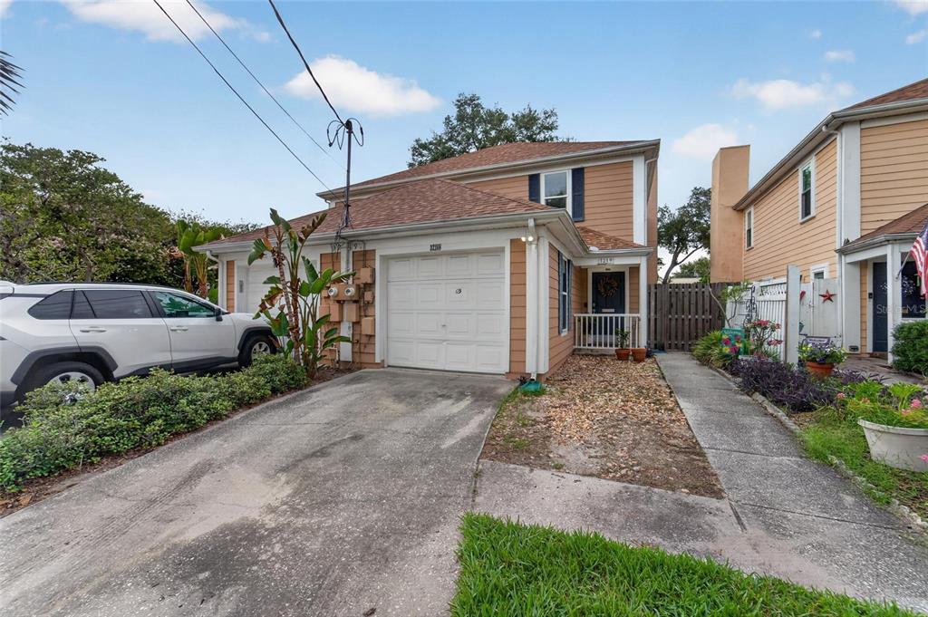 A two-story tan house with a single-car garage, a concrete driveway, and a small porch — 3219 W SANTIAGO STREET UNIT B, TAMPA, FL