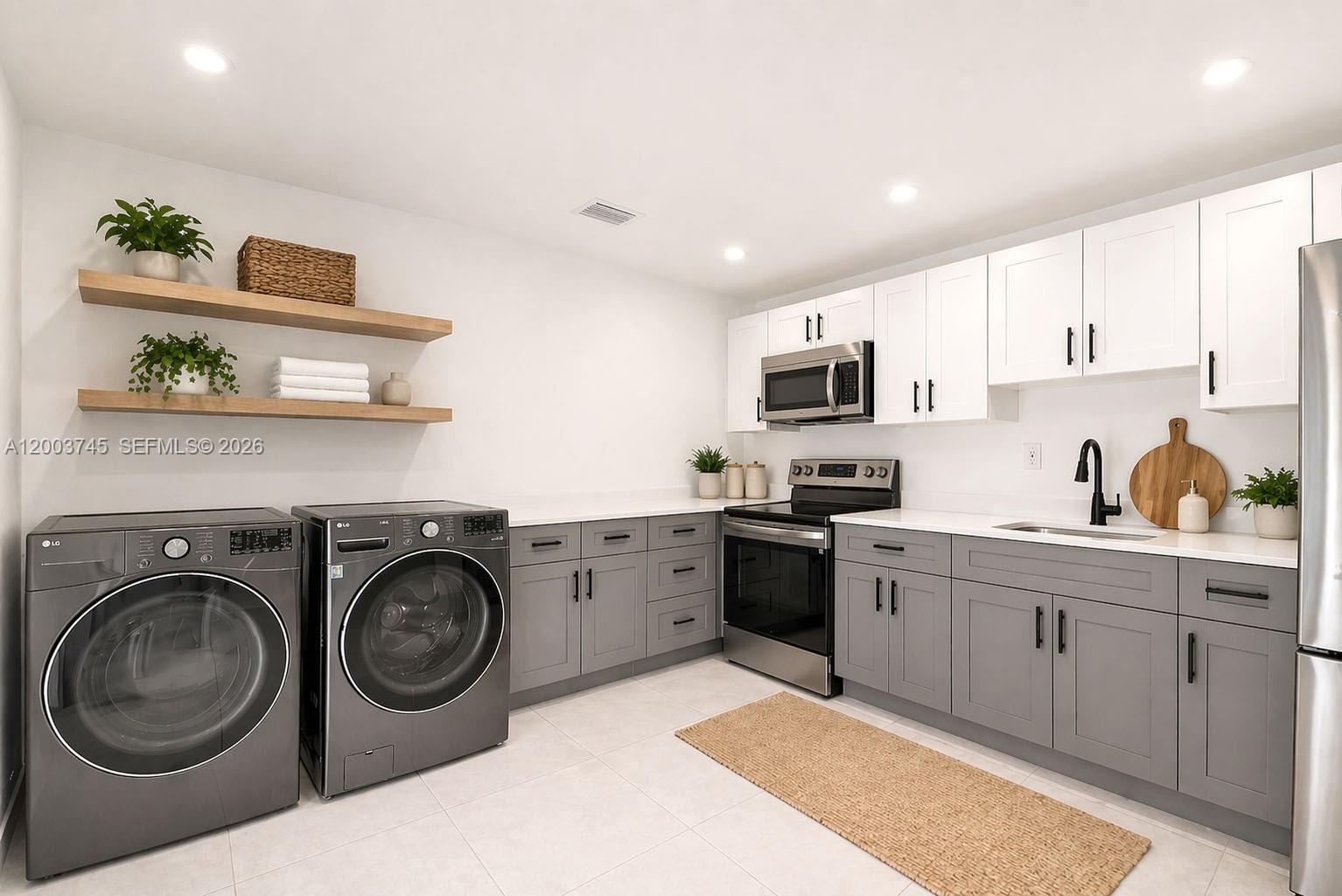 A laundry room features grey lower cabinets, white upper cabinets, stainless appliances, and floating wood shelves — 1102 NW 103rd St # 1, Miami FL 33150, MIAMI, FL