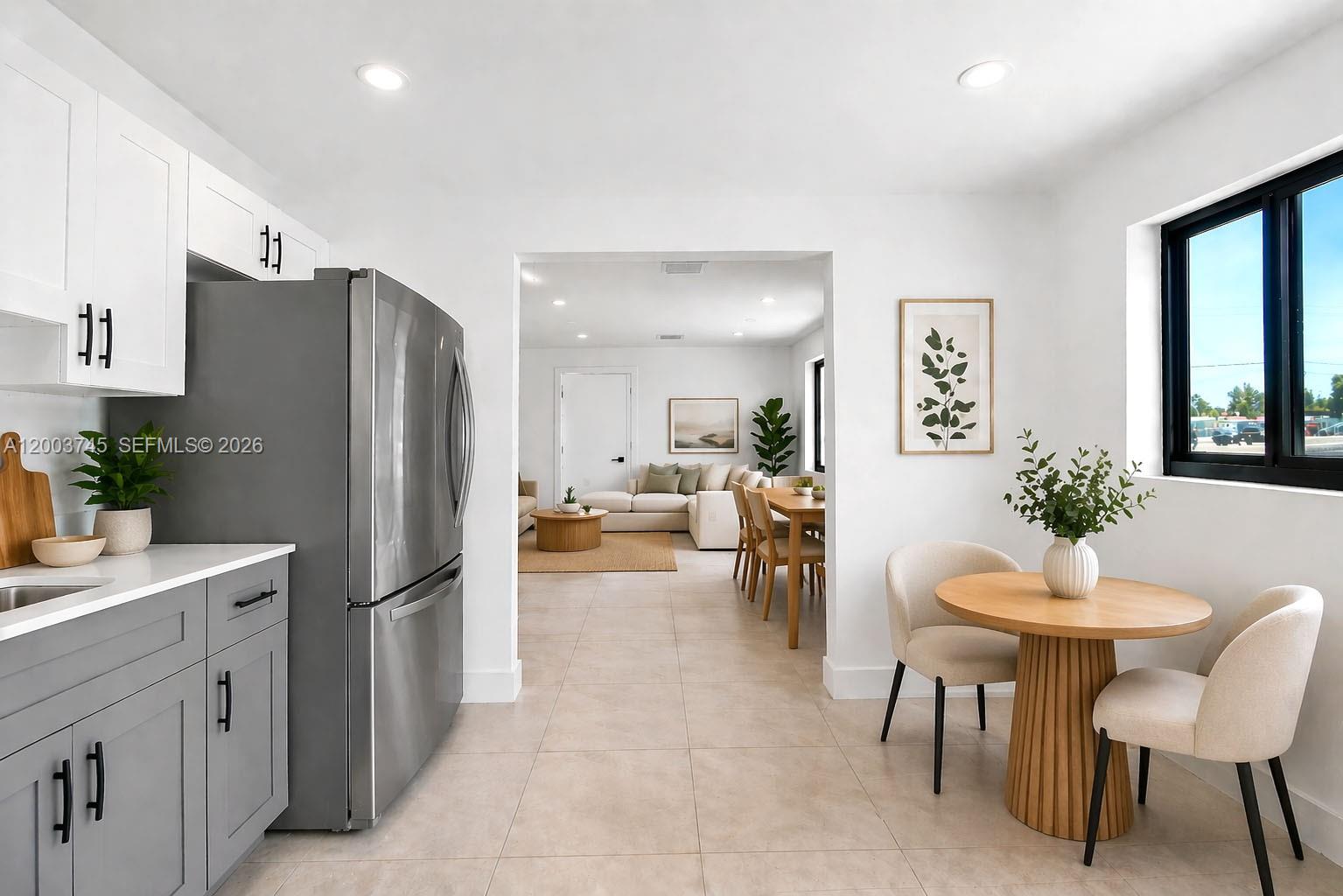 A kitchen with gray cabinets and stainless steel appliances opens into a dining area — 1102 NW 103rd St # 1, Miami FL 33150, MIAMI, FL
