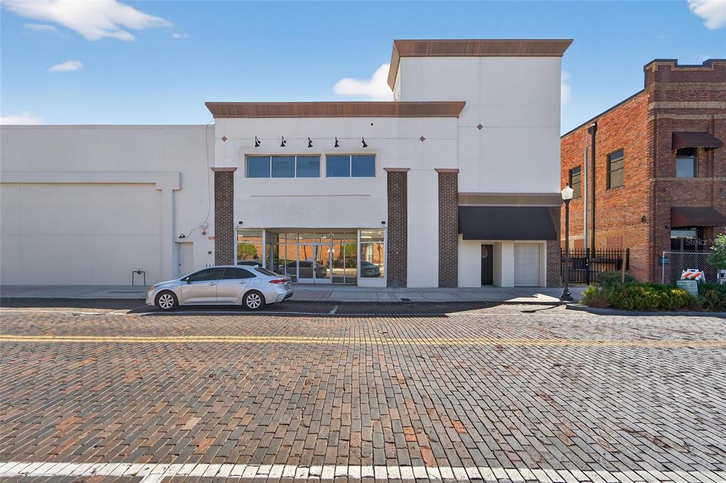 A silver sedan is parked in front of a commercial building with a brick-paved street — 106 N EVERS STREET, PLANT CITY, FL
