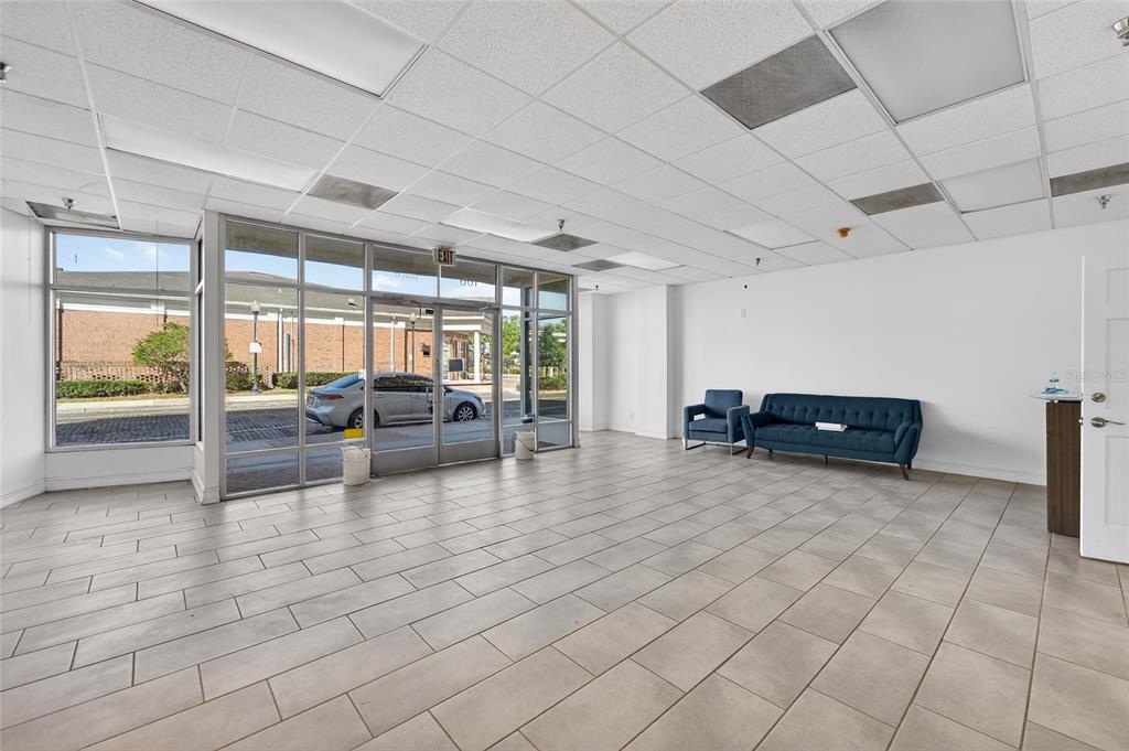 An empty commercial space features tile flooring, a drop ceiling, and a blue sofa set — 106 N EVERS STREET, PLANT CITY, FL