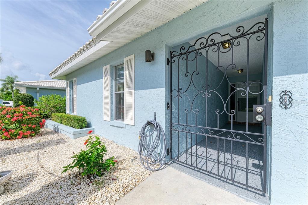A light blue house exterior features a decorative black metal gate leading to the front entrance — 804 67TH STREET W, BRADENTON, FL