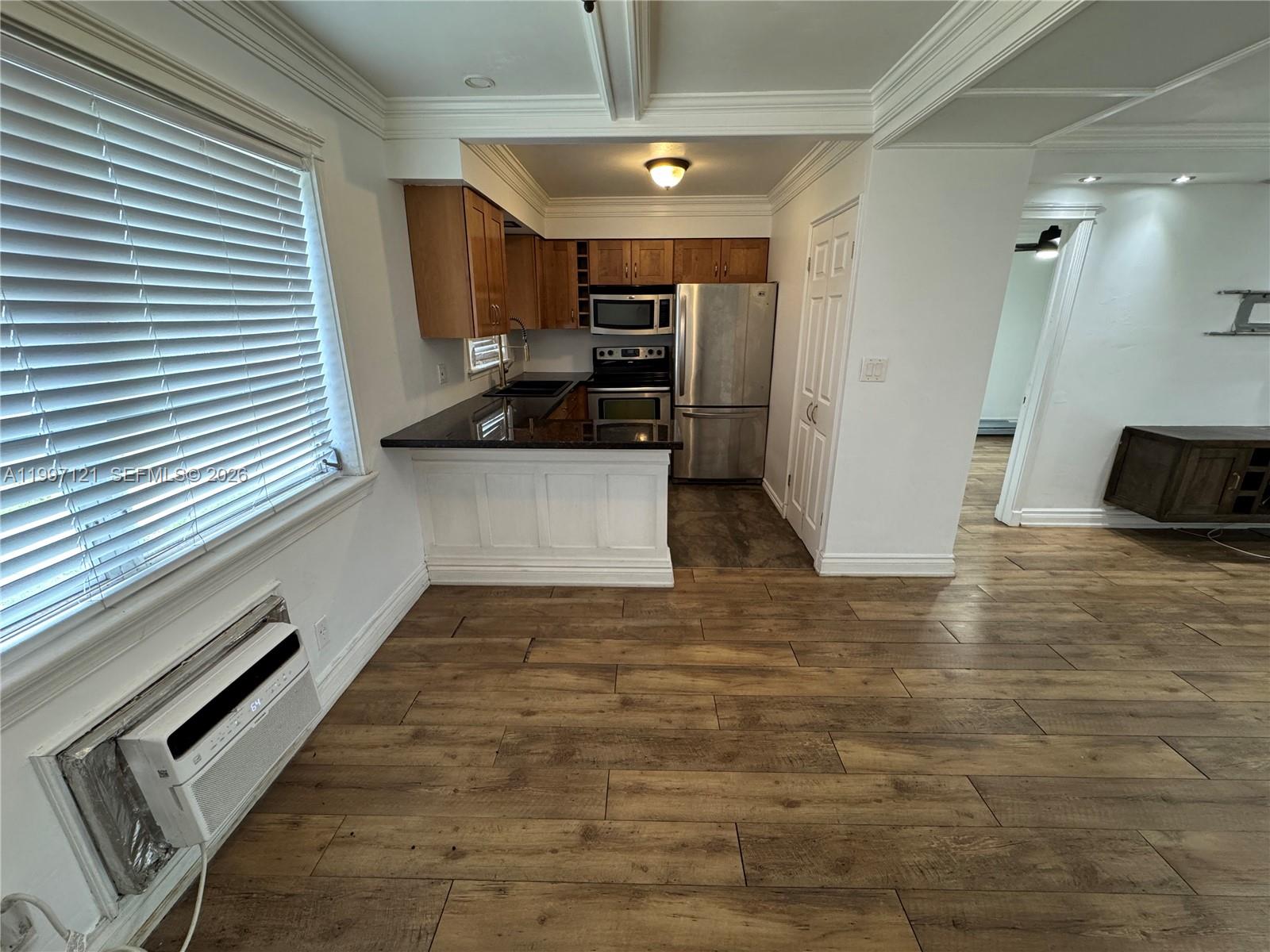 A kitchen with wood cabinets, stainless steel appliances, and dark countertops opens to a living area — 2000 Buchanan St # 3, Hollywood FL 33020, HOLLYWOOD, FL