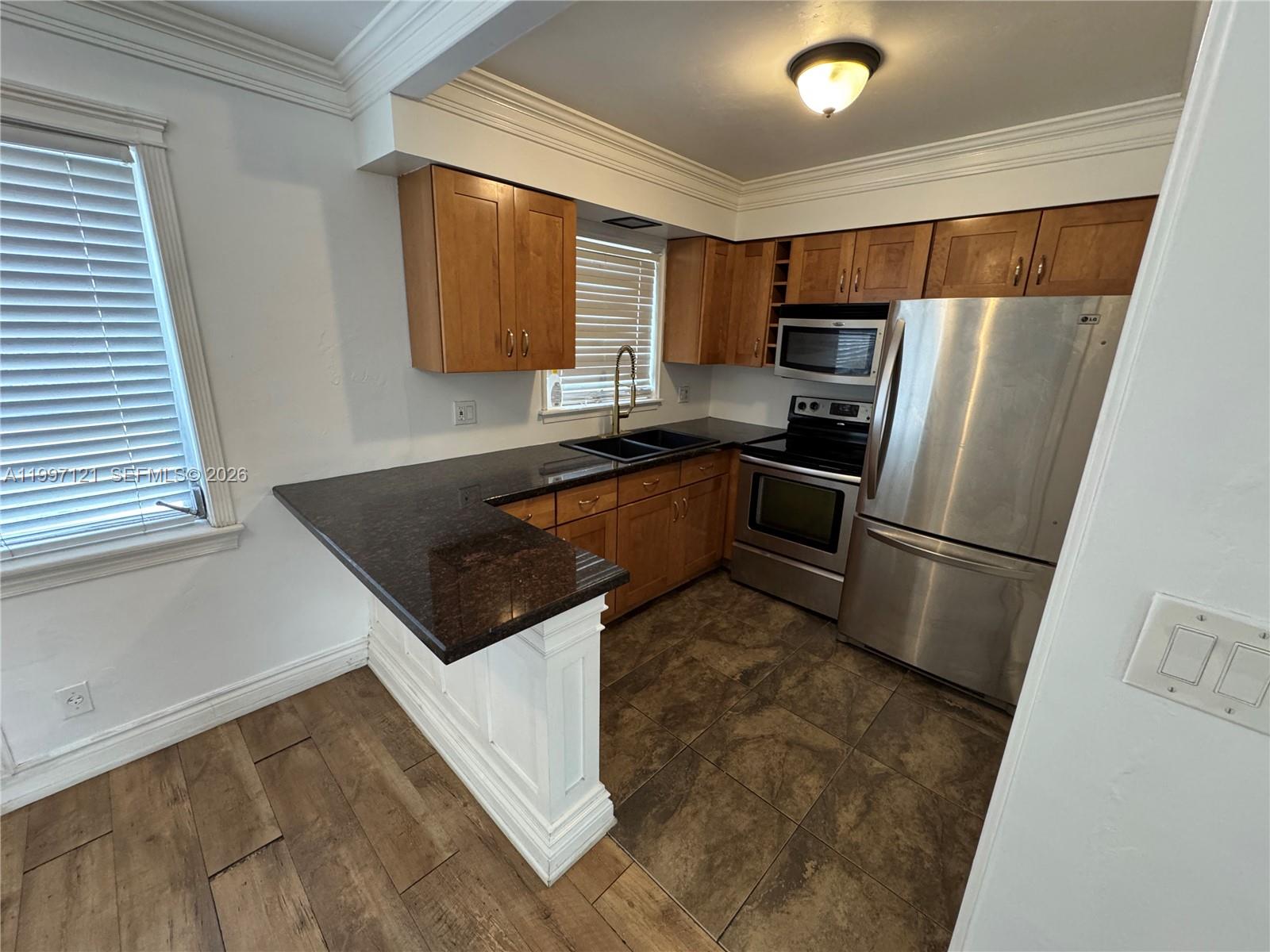 A kitchen features wood cabinets, dark granite countertops, stainless steel appliances, and tile flooring — 2000 Buchanan St # 3, Hollywood FL 33020, HOLLYWOOD, FL