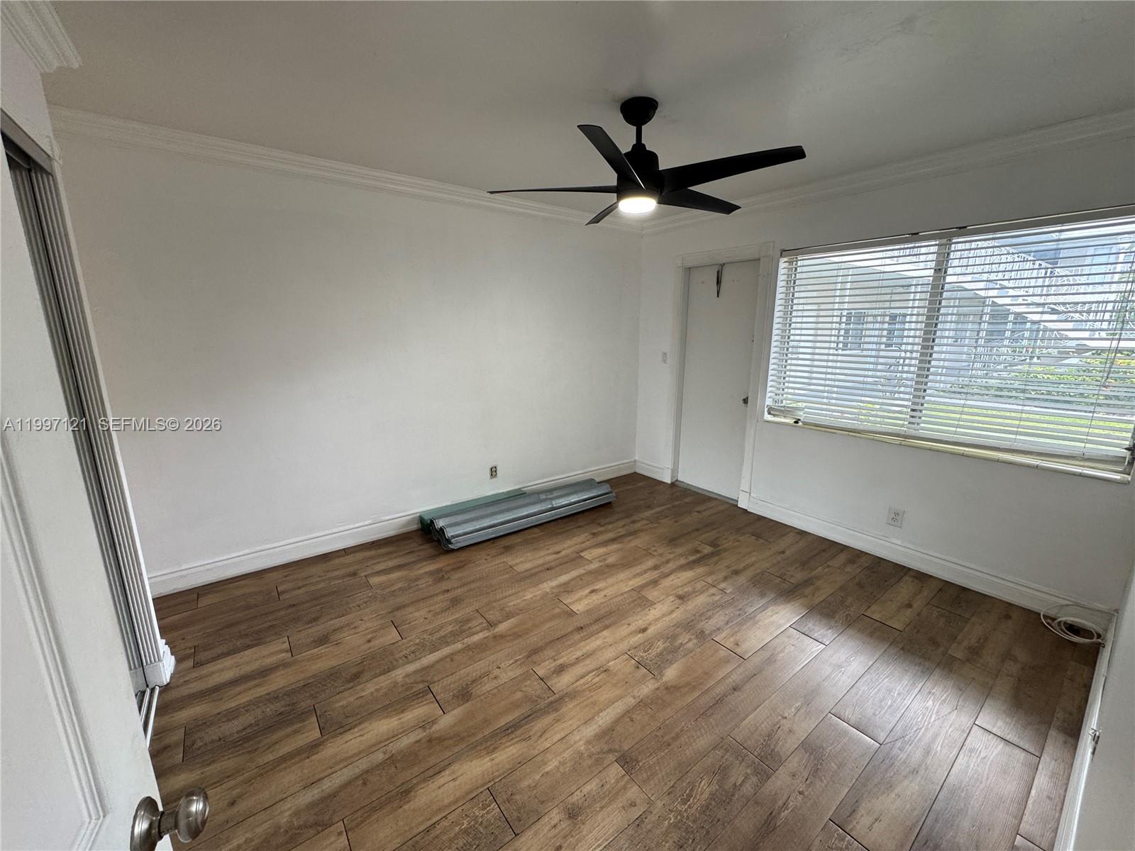 An empty room features white walls, wood-look tile flooring, a ceiling fan, and window blinds — 2000 Buchanan St # 3, Hollywood FL 33020, HOLLYWOOD, FL