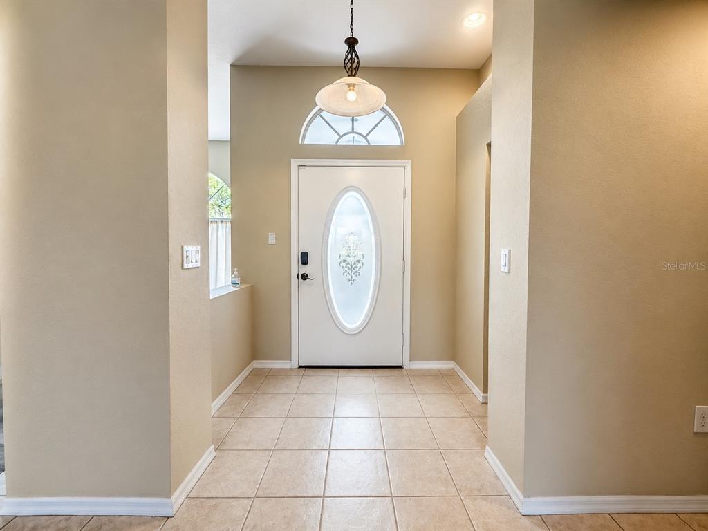 A tiled entryway features a white front door with an oval glass insert and transom window — 25264 PADRE LANE, PUNTA GORDA, FL