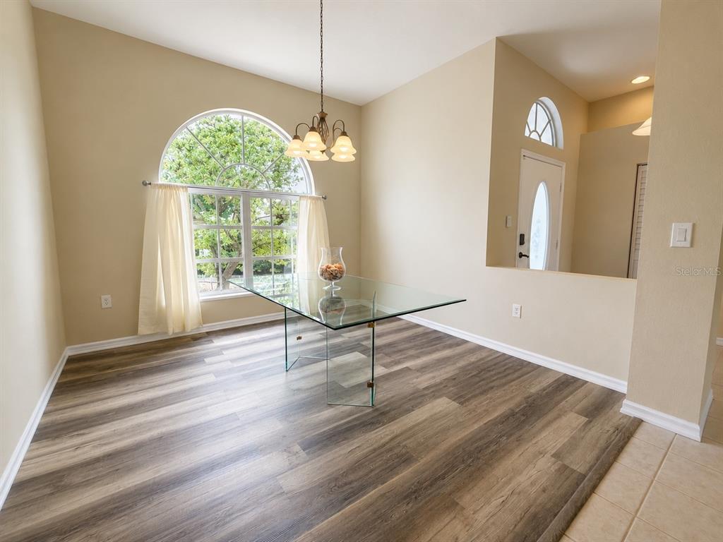A dining room with a glass table, arched window, and wood-look flooring — 25264 PADRE LANE, PUNTA GORDA, FL
