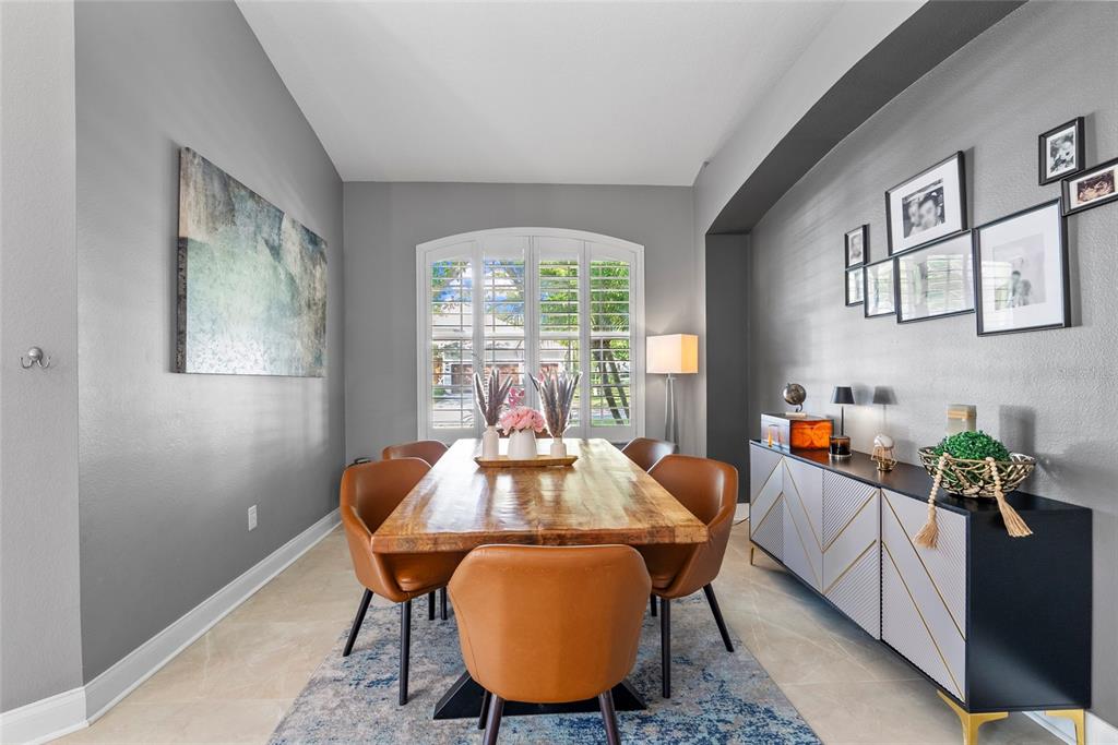 A dining room features a wooden table, leather chairs, a sideboard, and gray walls — 10602 ROCHESTER WAY, TAMPA, FL