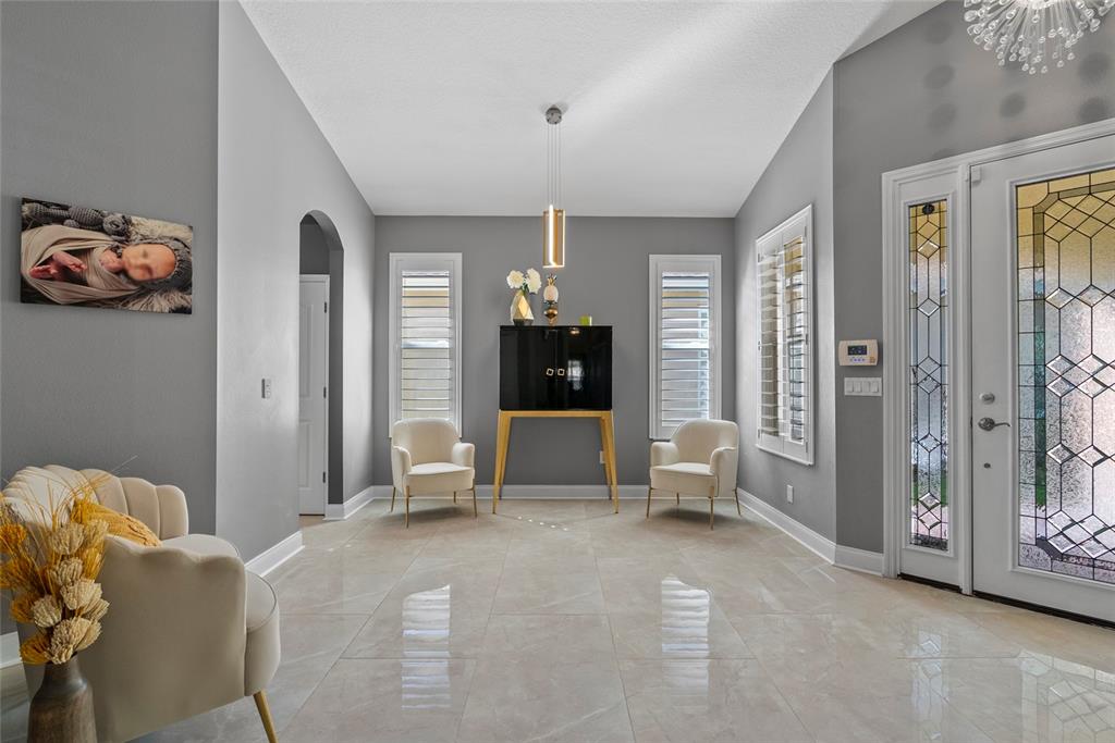 A bright foyer features gray walls, tile flooring, two white chairs, and a black cabinet — 10602 ROCHESTER WAY, TAMPA, FL