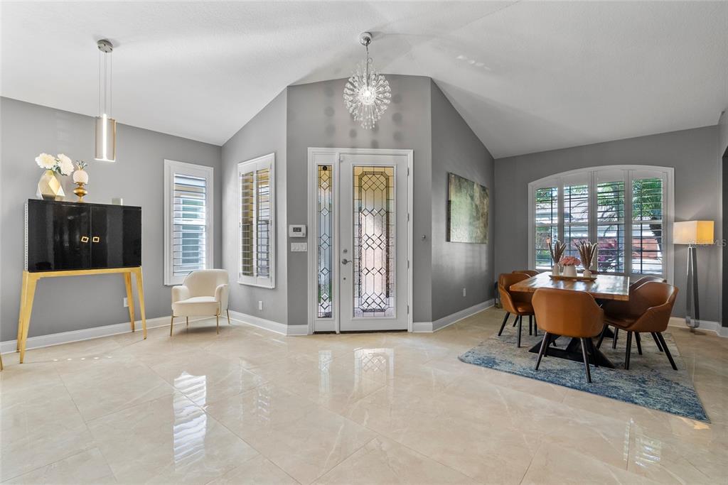 A bright foyer and dining area feature vaulted ceilings, gray walls, and polished tile floors — 10602 ROCHESTER WAY, TAMPA, FL
