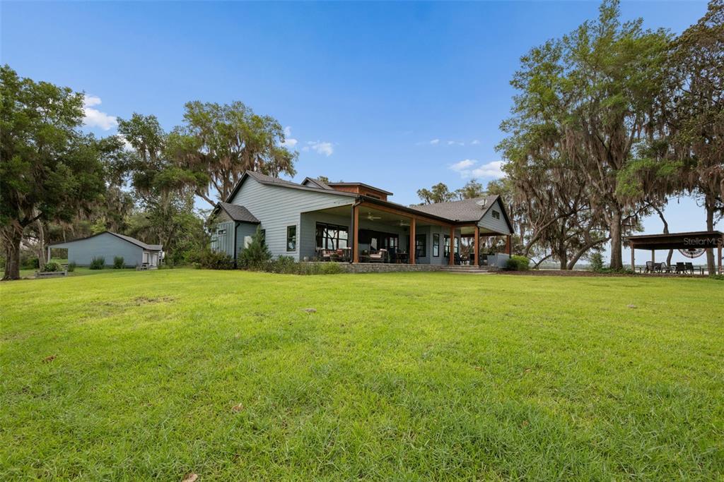 A large, gray, two-story house with a covered patio sits on a grassy lawn — 7229 PLEASANT POINT ROAD, KEYSTONE HEIGHTS, FL