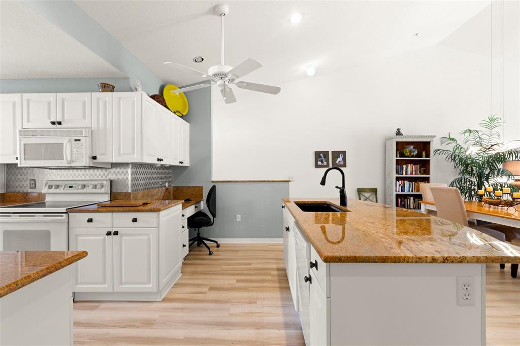 A kitchen with white cabinets, granite countertops, a center island, and a built-in desk area — 6758 FAIRVIEW TERRACE, BRADENTON, FL