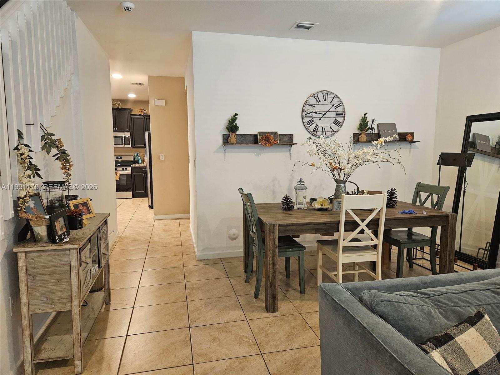 A dining area with a wooden table, chairs, and wall shelves sits beside a kitchen — 4117 NE 21st St, Homestead FL 33033, HOMESTEAD, FL