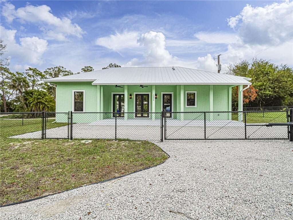 A light green single-story house with a metal roof and a chain-link fenced yard — 12906 83rd Avenue, Sebastian FL 32958, SEBASTIAN, FL